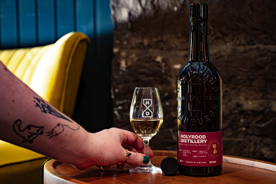 A bottle of Holyrood Distillery Single Cask Whisky #147 next to a glass of whisky.
